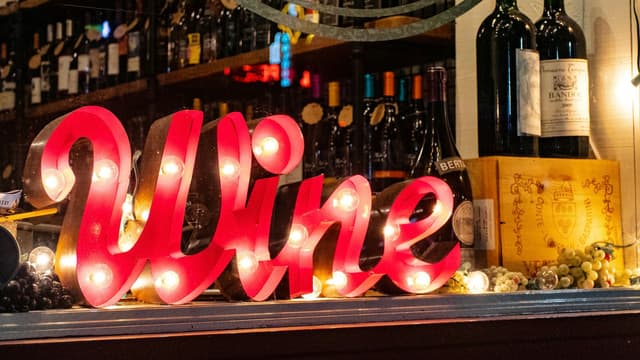 A lighted sign on the counter of a wine bar