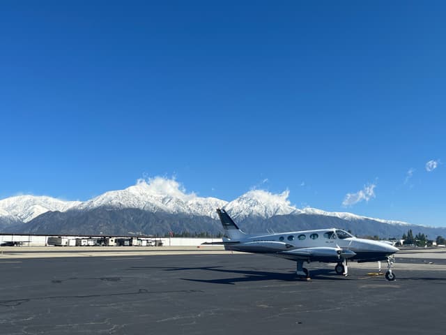 A mutli-engine aircraft parked at Cable Airport with mountains in the background